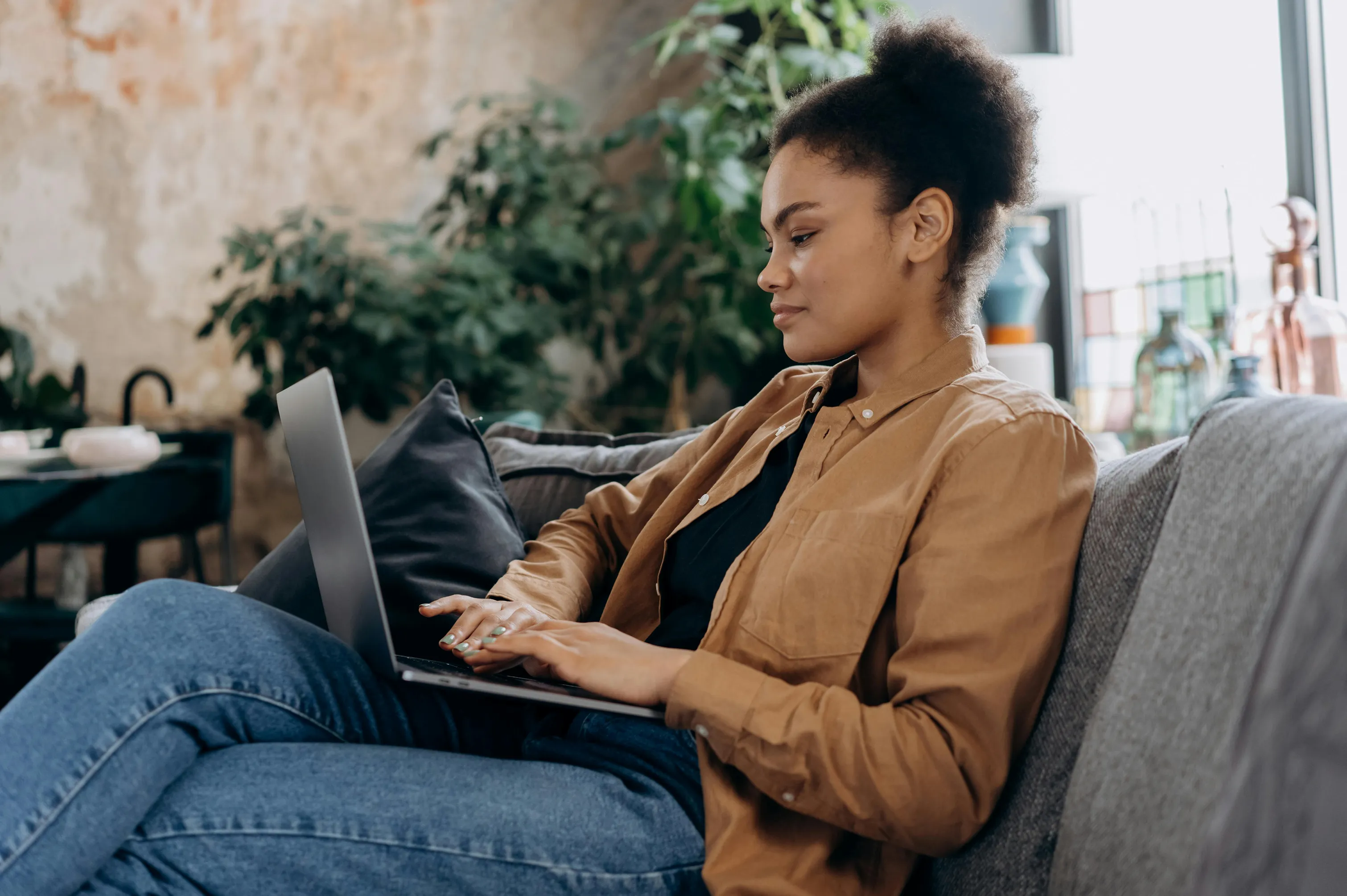Woman sitting on a couch using laptop with a hopeful expression